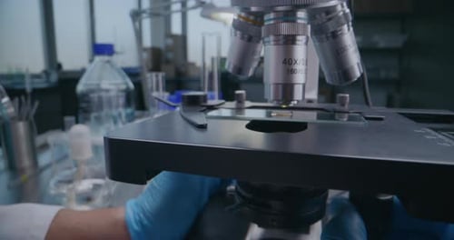 Close Up of Professional Microbiologist Setting Up Microscope for Analysis