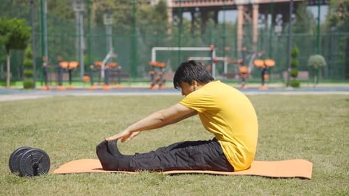 Young Adult Man Stretching on a Mat Outdoors
