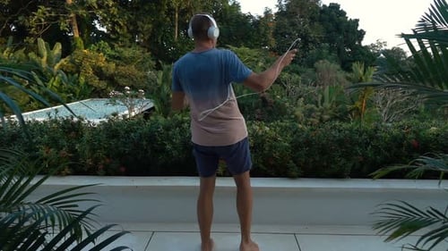 Happy young man dancing and listening to music on his smartphone at his terrace