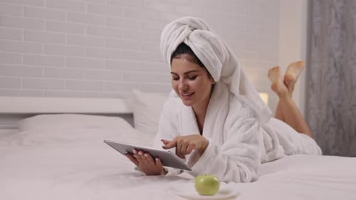 Woman in Bathrobe Relaxes with Tablet and Apple
