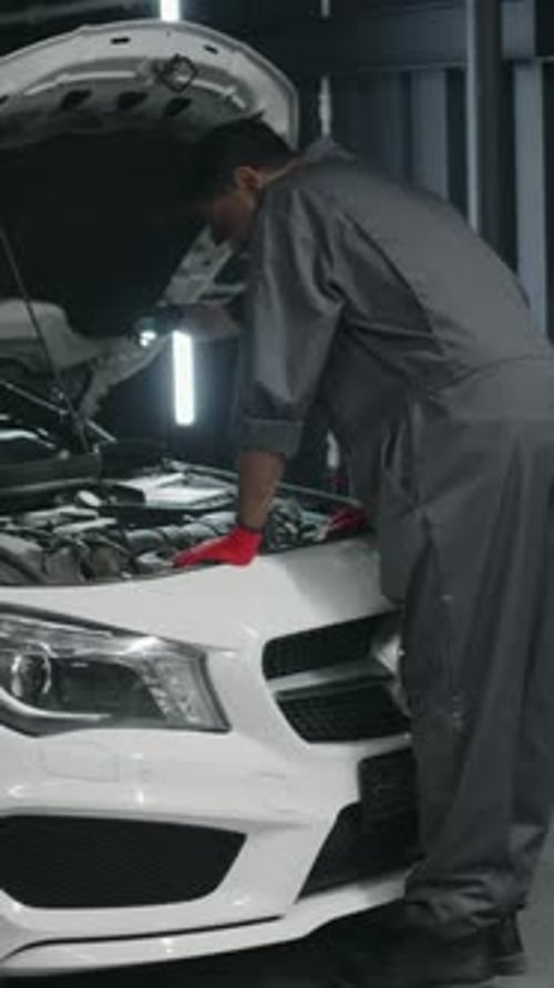 Diverse Mechanics Servicing White Car in Workshop