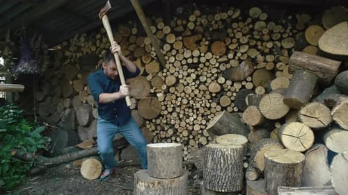 Slow Motion Video of a Man Chopping a Log with an Ax