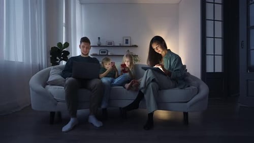 Family Together Relaxing on Couch Using Electronic Devices