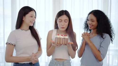 Young asian girl celebrates her birthday surrounded by close friends, young woman blows out candles
