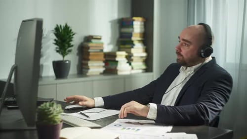 A Businessman Puts on Headphones for a Zoom Meeting and Greets Partners