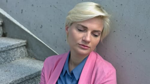 Traurige Geschäftsfrau in Depression sitzt auf der Betontreppe.
