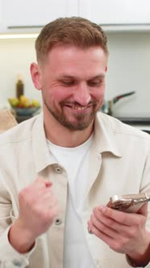 Man Looking at Phone, Reacting with Excitement and Joy