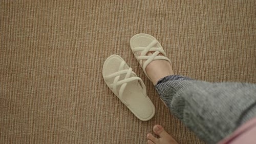 Woman Puts on Fashionable Slippers on Carpet