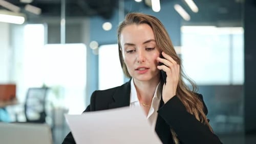 Business Woman Discussing Documents on Phone in Office