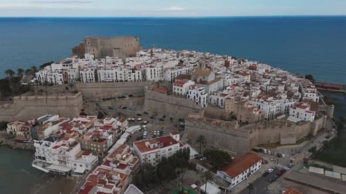 Drone over coastline and castle above rocky beach terrain