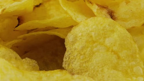 Potato chips rotating close up on culinary parchment.