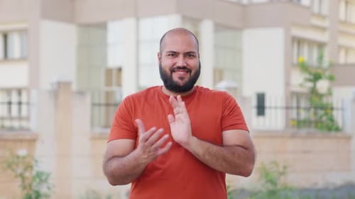 Man Smiling and Clapping Hands Outside Building