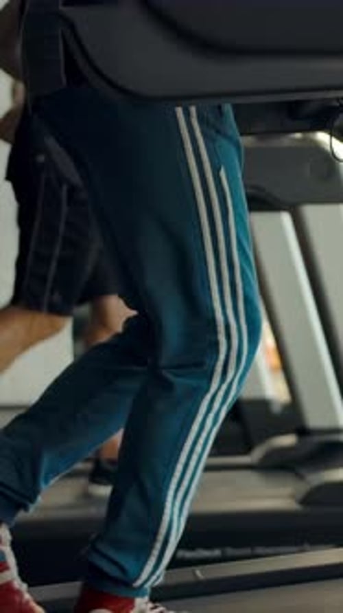 Vertical of Three People Running on Treadmills in a Gym Side Viewv
