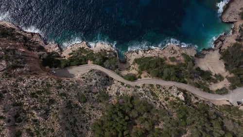 Aerial Footage Flying Over a Winding Road Along a Rugged Coastline Revealing a Beautiful Turquoise