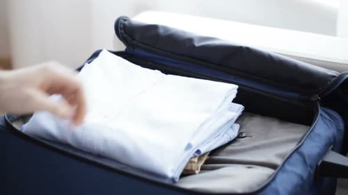 Man packing clothes into travel bag at home close up for vacation trip