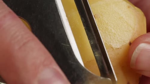 Potato Peeling with Silver Kitchen Peeler in Close Up