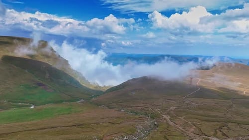 Midday cloudy mountain view. Clouds drift over green hills and rocky peaks