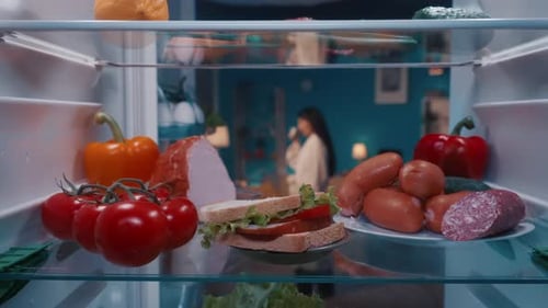 Refrigerator with Products on the Shelves Inside View The Door Opens an Asian Woman in a Bathrobe