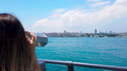 Young Woman Using Telescope Overlooking City on the Water