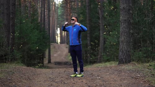 Fit Man is Doing Warmup Exercises and Stretching His Legs on a Scenic Trail in a Serene Pine Forest