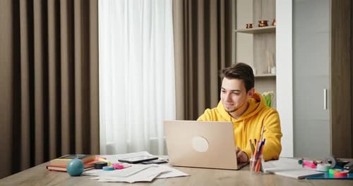 Young Guy Working at Home Home Office Sitting at Desk Working on Laptop Freelancer Smiling