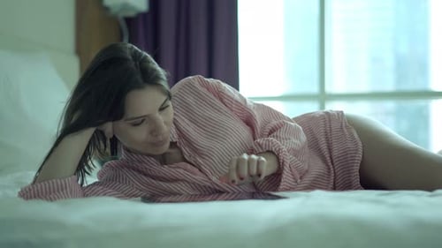 Woman Lying on Bed Using Tablet
