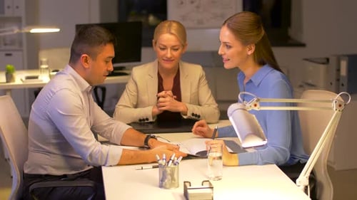 Happy business team works late at night in a modern office setting