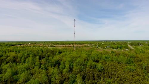 Aerial shot flying towards a radio tower in a rural area