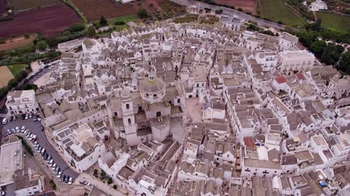 Aerial view of white town with cloudy sky and famous church, Locorotondo, Italy.
