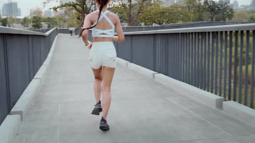 Young fitness woman in sportswear jogging in city park