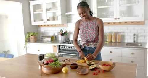 Smiling Woman Preparing Salad in Bright Kitchen