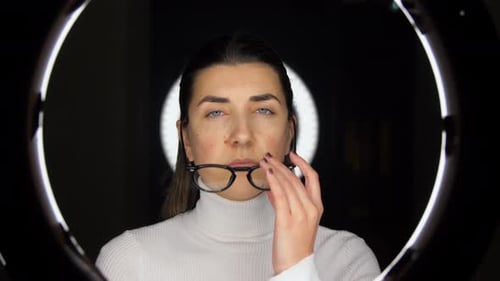 Woman Putting on Glasses Under Ring Light Indoors