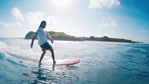 Male surfer rides the wave. Man surfs the perfect blue wave during sunny day in Maldives