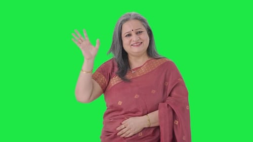 Happy Indian old woman waving and saying Hello Green screen