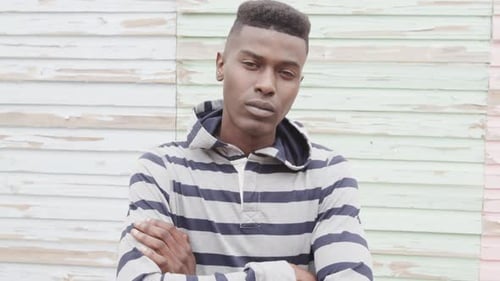 Portrait of african american man crossing arms and smiling in front of painted boards, slow motion
