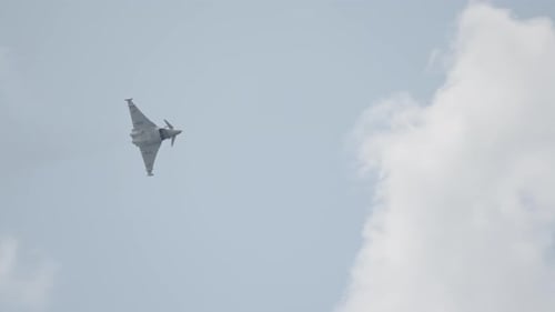 Military Jet Flying High in Cloudy Sky