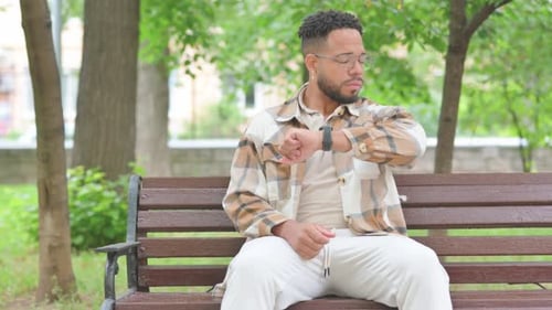 Young Man Waiting on Park Bench Checking Watch