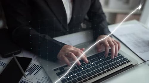 Business professional analyzing financial data with laptop and stock market trends visualized throug