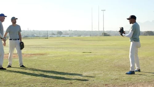 Ball toss prompting three male baseball players rotating catch in outfield, resuming duo tosses
