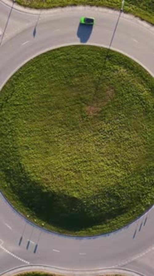 Vertical slow drone static above Katlakalns roundabout with green central island, car traffic