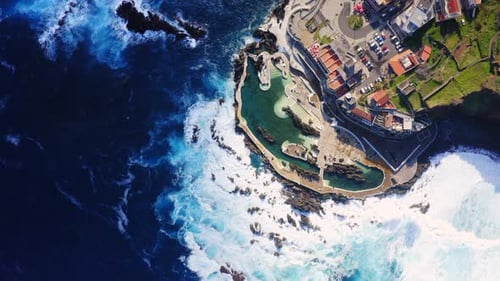 High angle top down of crashing waves against rocks with white foam. Natural Pool in Porto Moniz,Mad