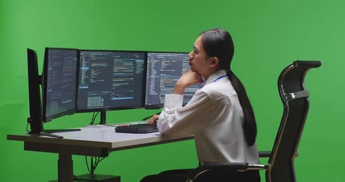 Woman Developer Thinking While Write Code With Multiple Computer Screens In Green Screen Studio