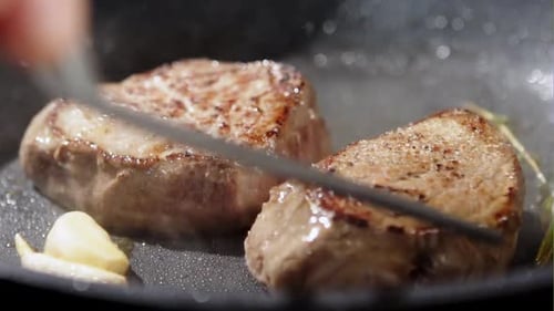 Steaks Sizzling in a Hot Pan with Garlic