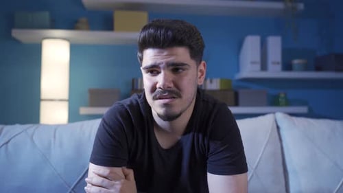 Emotional man at home with tears in his eyes.