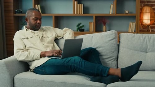 Man Working on Laptop Computer Relaxing on Couch
