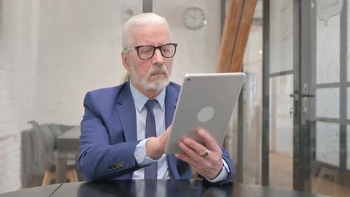 Man in Suit Using Tablet Device at Table