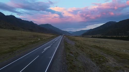 Aerial View of a Valley with a River and Road Surrounded By Mountains at Sunset