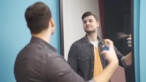 Stylish Man Sprays Cologne in Front of Mirror
