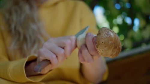 A Woman Cleaning Porcini Mushrooms in the Garden with a Knife