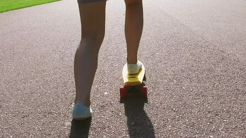 Woman on skateboard riding along asphalt path